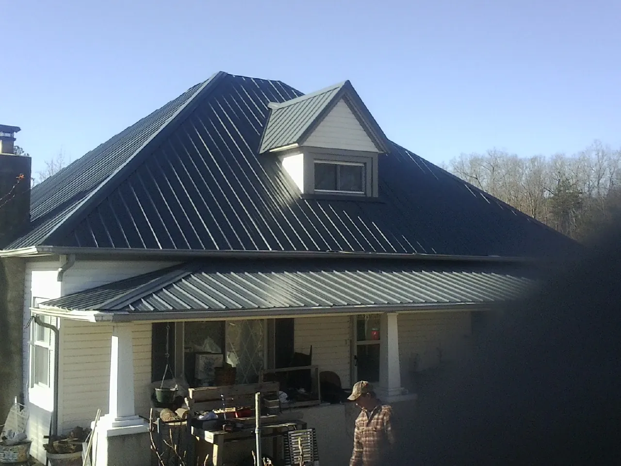 Dark blue standing seam metal roof with a dormer above a front porch in Garden City