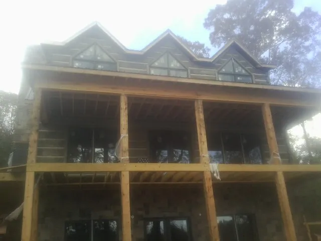 Dormers and porch framing on a large log home under construction — Roof Coating work by our crew in Garden City